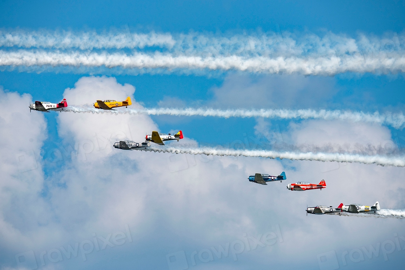 A formation of vintage warbirds trailing smoke against a blue sky at an airshow